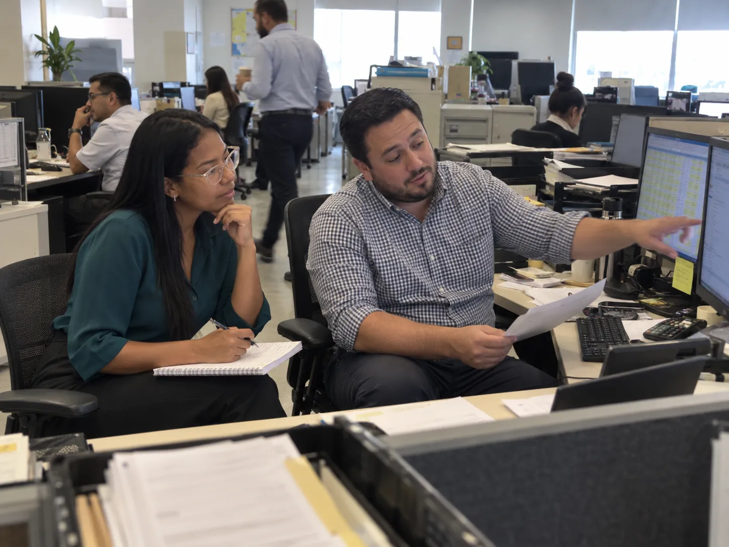 Yanina Bazurto Roa taking notes as an HR officer walks her through his leave-request spreadsheet